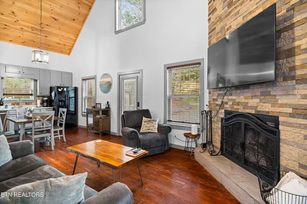 a living room with stainless steel appliances furniture a rug and a kitchen view