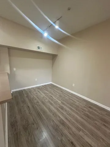 a view of a kitchen with a sink wooden floor and an empty room