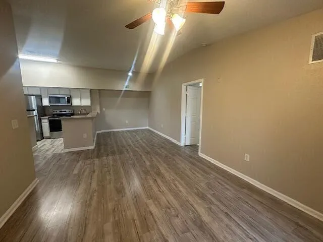 a view of empty room with wooden floor and fan