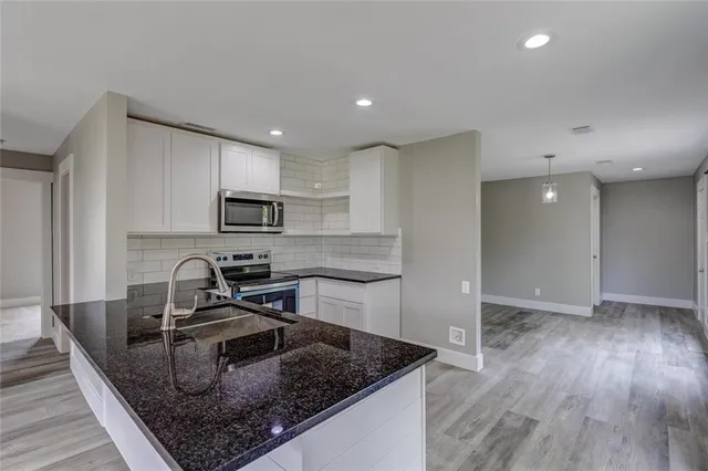 a kitchen with kitchen island granite countertop a sink a counter space appliances and cabinets