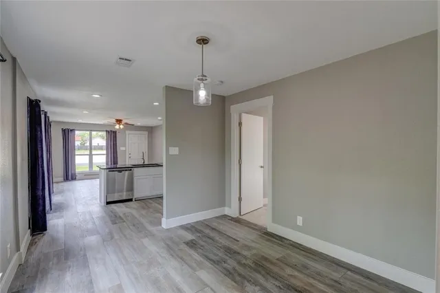 a view of a hallway with wooden floor and a kitchen