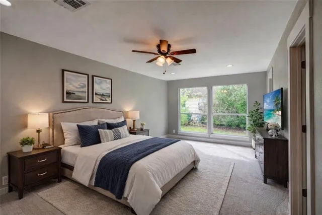 a bedroom with a large bed and a chandelier fan
