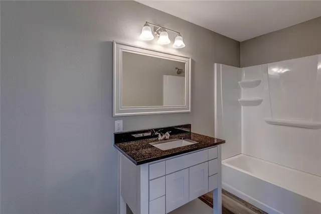 a bathroom with a granite countertop sink a toilet and bathtub