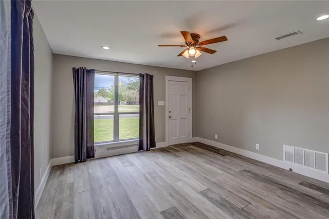 a view of an empty room with wooden floor and a window