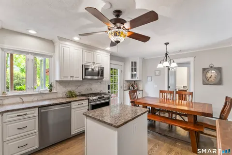a kitchen with a refrigerator a sink dishwasher a dining table and chairs with wooden floor