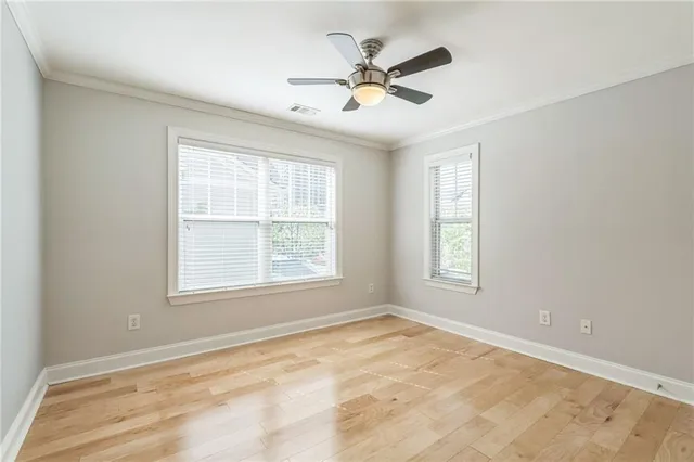 an empty room with chandelier fan and windows