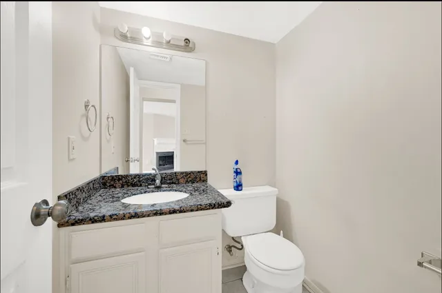 a bathroom with a granite countertop sink toilet and mirror