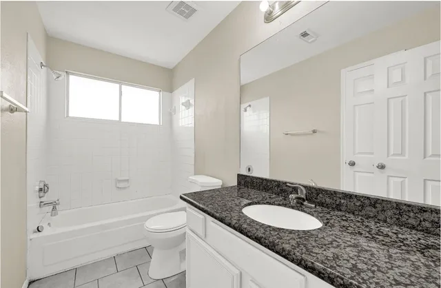 a bathroom with a granite countertop sink toilet a large mirror a bathtub and shower
