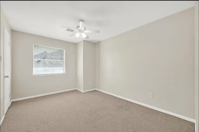 an empty room with a window and a ceiling fan