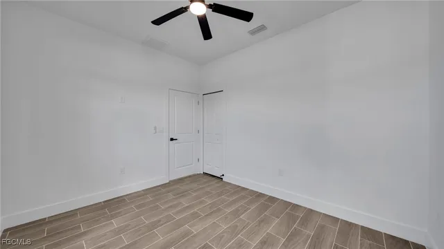 an empty room with a ceiling fan and wooden floor