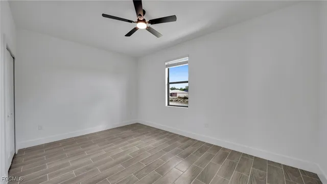 an empty room with a window and ceiling fan