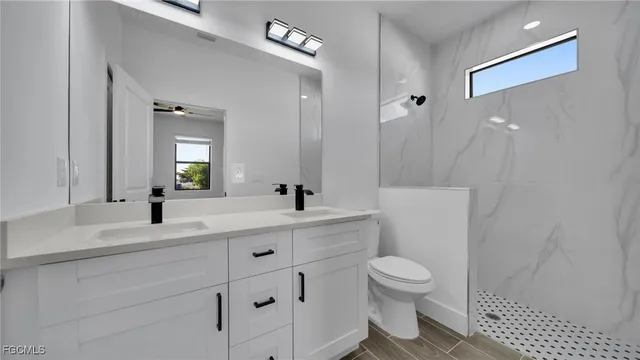 a bathroom with a toilet a sink a light fixture and a mirror