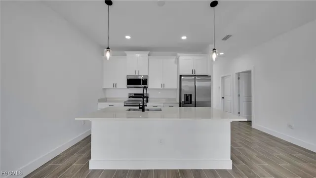 a large kitchen with stainless steel appliances a large counter top a sink a refrigerator and a window