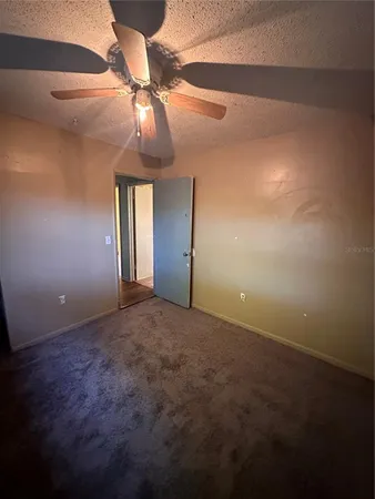 a view of an empty room and chandelier fan