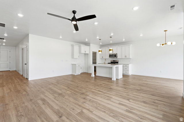401 West 3085 South, Unit 329 Nibley, UT 84321 - Photo 14 of 34 Unfurnished living room featuring ceiling fan, light wood finished floors, and suspended lighting