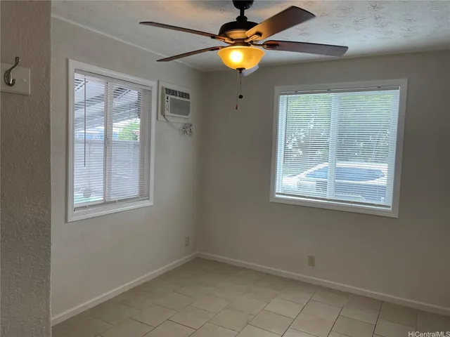 a view of an empty room with chandelier fan and a window