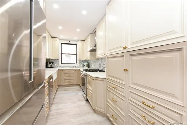 a large white kitchen with granite countertop a sink a window and stainless steel appliances