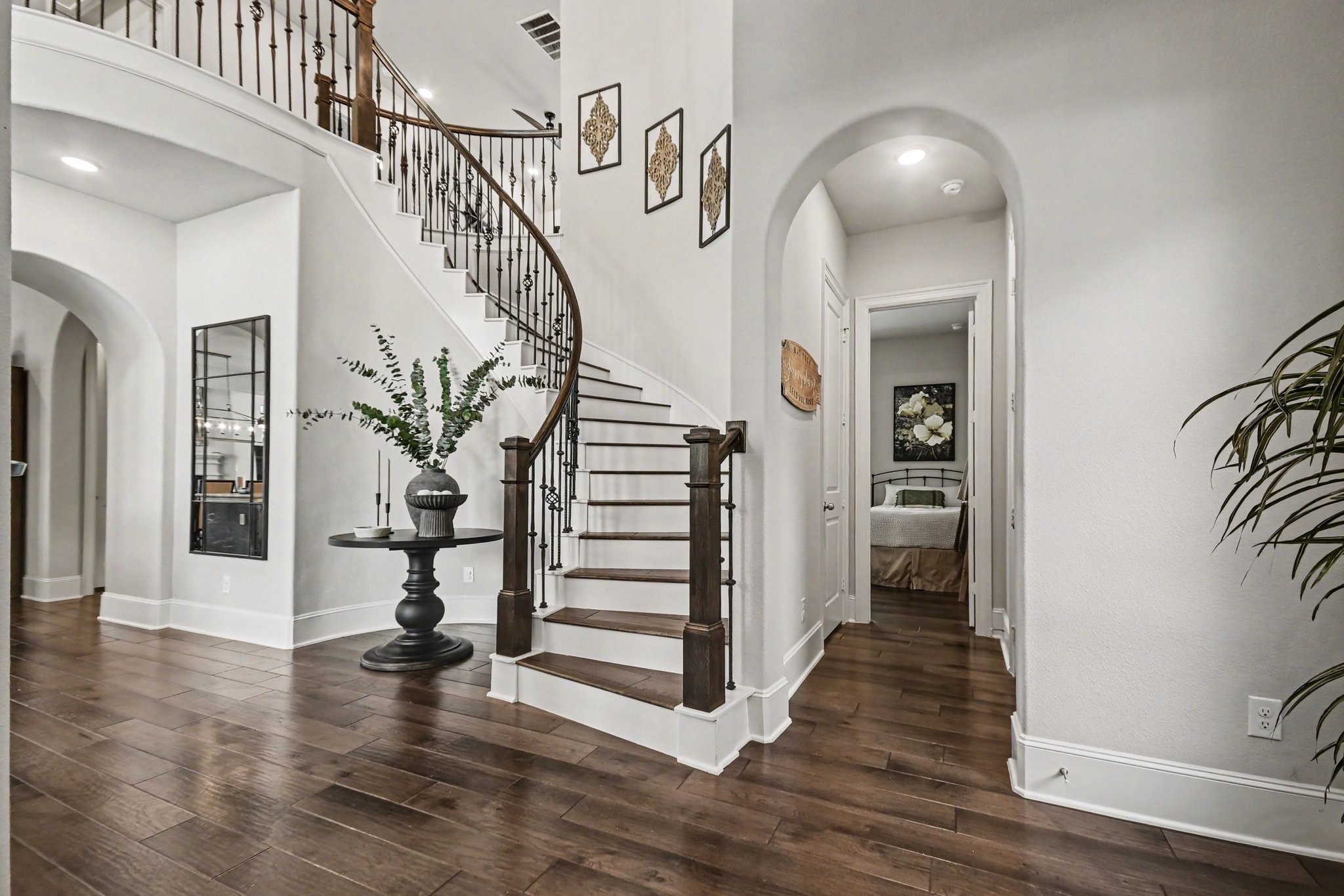 641 Kickapoo Court Webster, TX 77598 - Photo 1 of 39 Welcome to 641 Kickapoo, An elegant entryway with a graceful curved staircase, rich wood flooring, and high ceilings. The space is bright and inviting, featuring tasteful decor and an arched hallway leading to additional rooms.