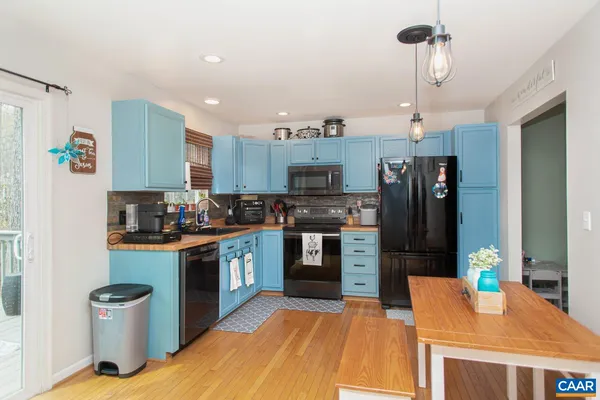 a kitchen with stainless steel appliances kitchen island granite countertop a refrigerator a stove top oven a sink dishwasher and a dining table with wooden floor