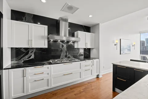 a kitchen with granite countertop white cabinets and stainless steel appliances