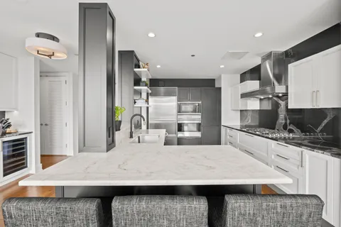 a kitchen with kitchen island a counter top space a sink stainless steel appliances and cabinets