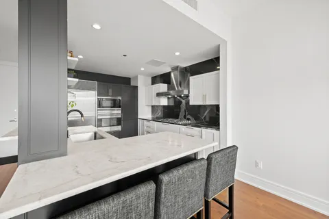 a living room with stainless steel appliances kitchen island granite countertop furniture and a wooden floor