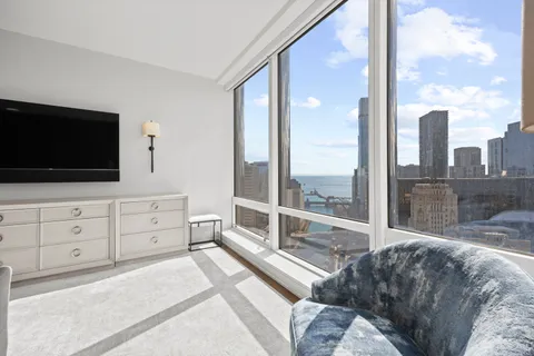 a living room with furniture a flat screen tv and a floor to ceiling window