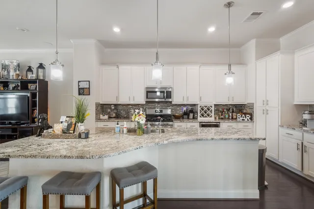 a kitchen with stainless steel appliances granite countertop a kitchen island a stove a sink a oven a dining table and chairs