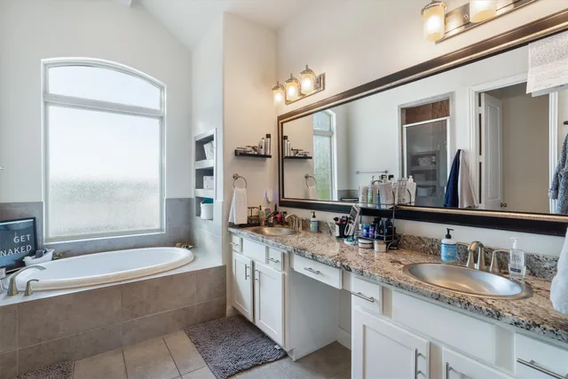 a bathroom with a granite countertop tub sink and mirror
