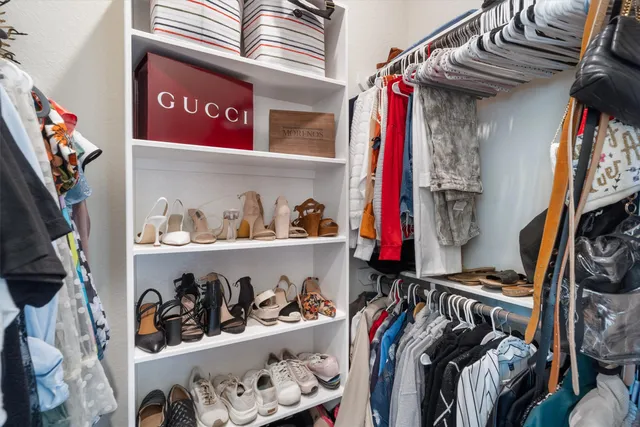a view of walk in closet with clothes and shoes