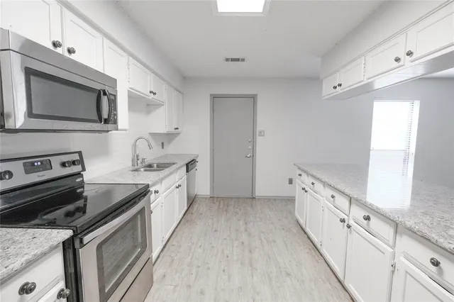 a kitchen with white cabinets stainless steel appliances and sink