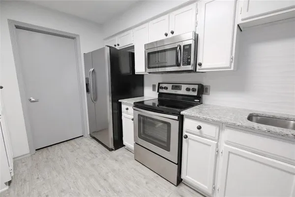 a kitchen with stainless steel appliances granite countertop a refrigerator a stove and a sink