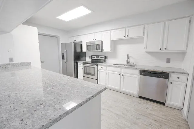 a kitchen with stainless steel appliances a sink a stove a refrigerator cabinets and a window