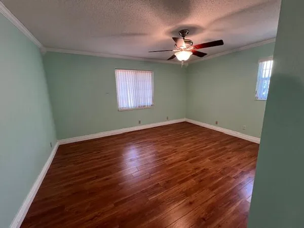 a view of a room with wooden floor a chandelier fan and a window