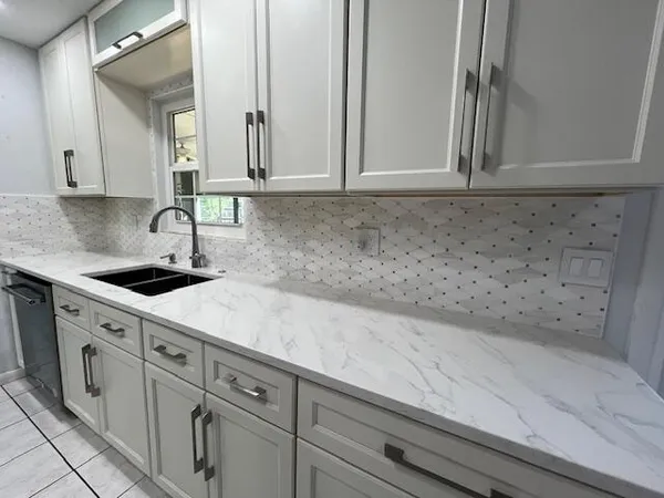 a kitchen with white cabinets and sink