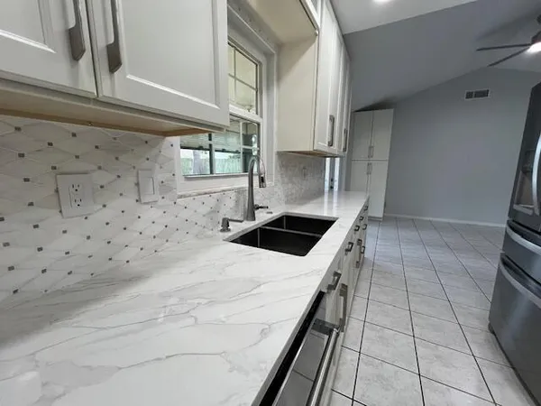 a kitchen with granite countertop a sink a stove top oven and cabinets