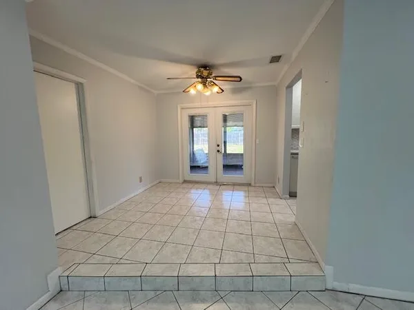 a view of an empty room with window and chandelier fan