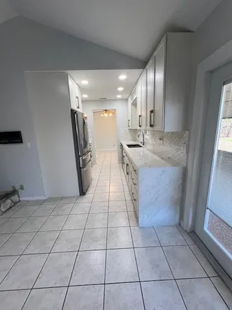 a large white kitchen with a sink a counter top space and stainless steel appliances