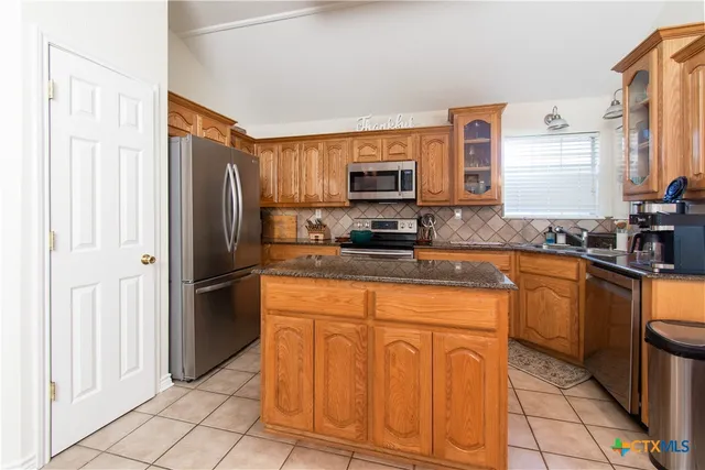 a kitchen with stainless steel appliances granite countertop a refrigerator and a stove top oven