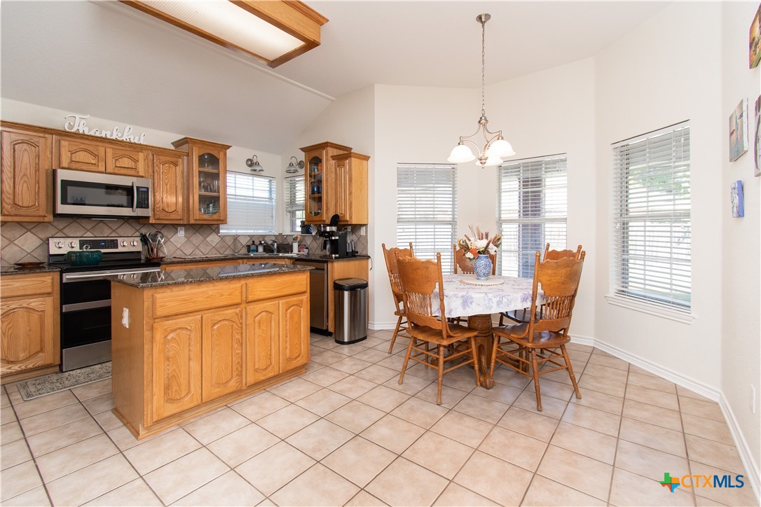 103 Corral Court Harker Heights, TX 76548 - Photo 7 of 27 a kitchen with stainless steel appliances granite countertop a stove a sink dishwasher a dining table and chairs with wooden floor