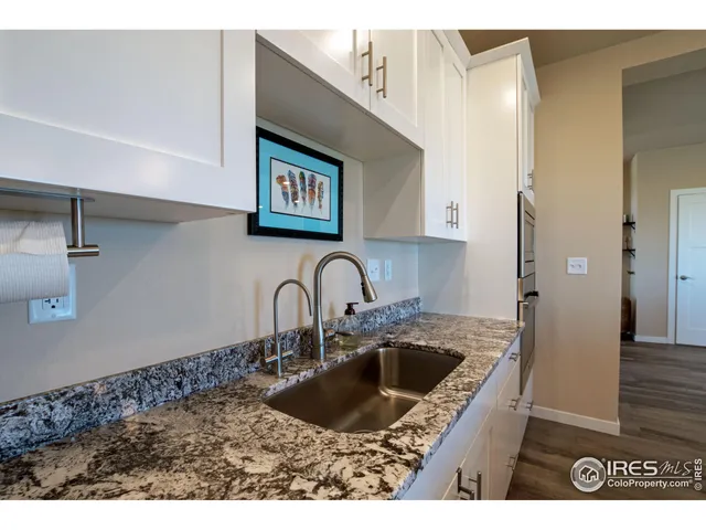 a kitchen with stainless steel appliances granite countertop a table chairs refrigerator and sink