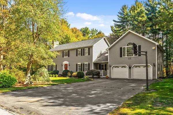 a front view of a house with a garden and trees