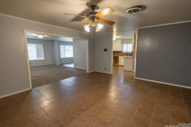 en empty room with windows and ceiling fan