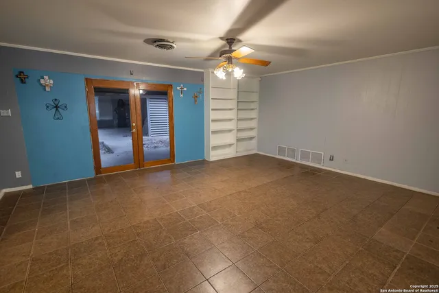 an empty room with windows and fan