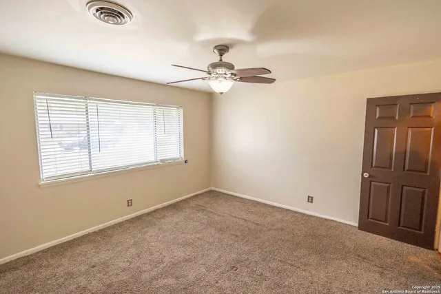 an empty room with windows and fan