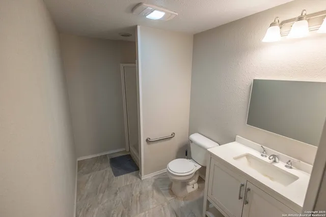 a bathroom with a granite countertop sink a toilet and a shower