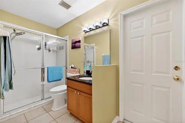 a bathroom with a granite countertop sink a toilet and shower
