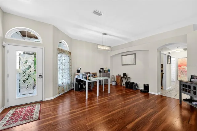 a dining room with wooden floor a chandelier a wooden table and chairs
