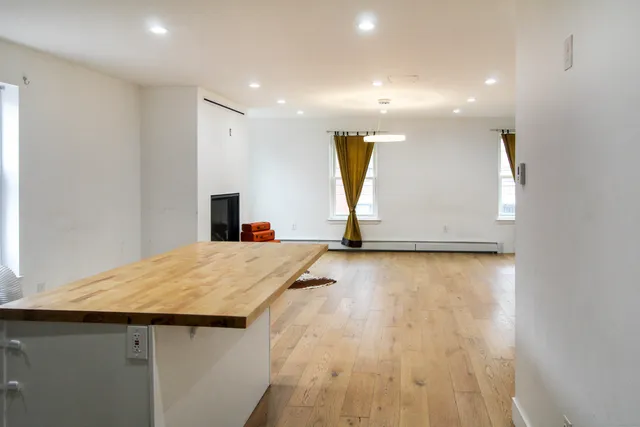 a kitchen with stainless steel appliances kitchen island a refrigerator sink and white cabinets