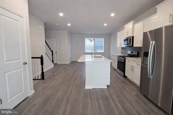 a kitchen with kitchen island wooden floors appliances and sink